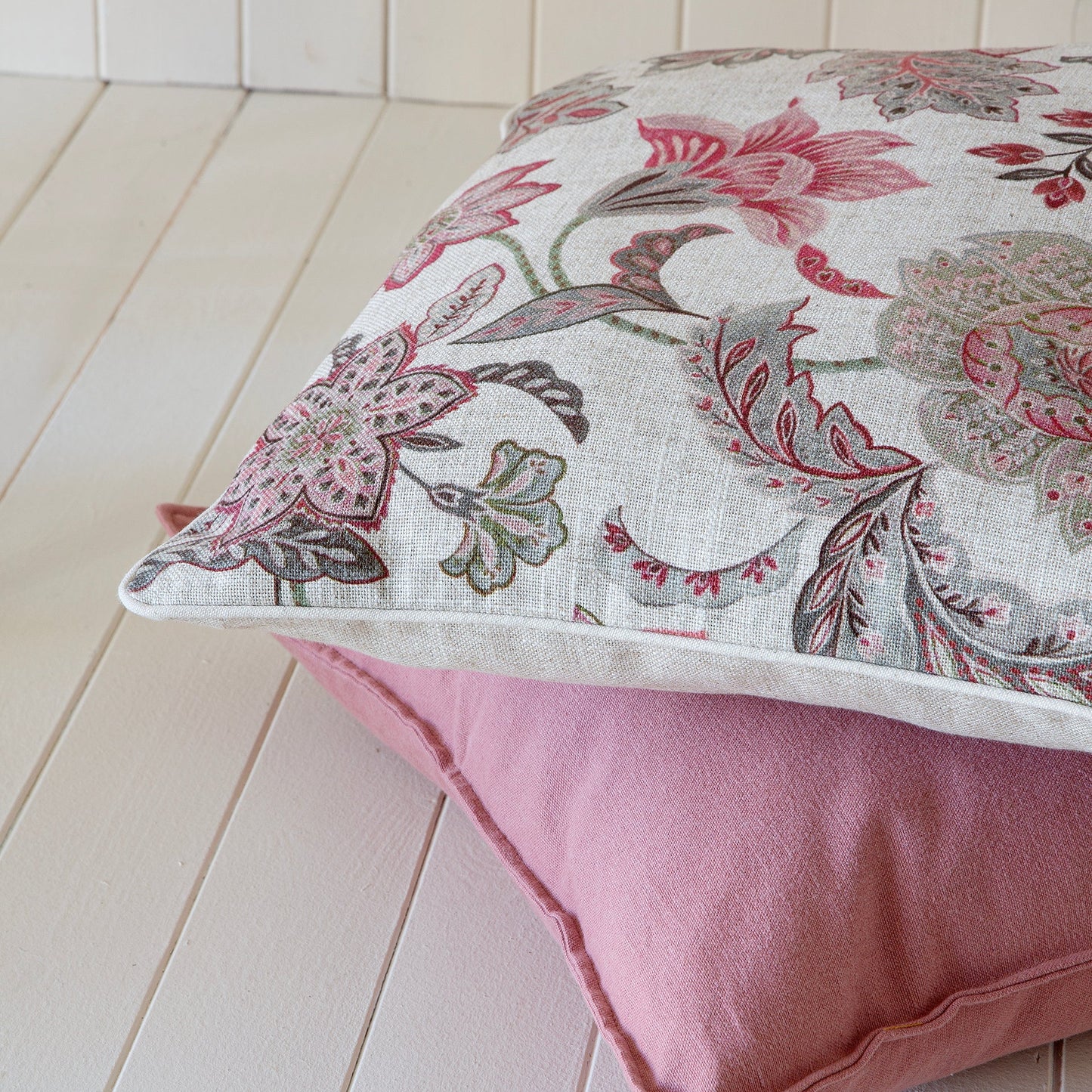 Floral-patterned cushion 50x50cm on a pink pillow against a white wooden background