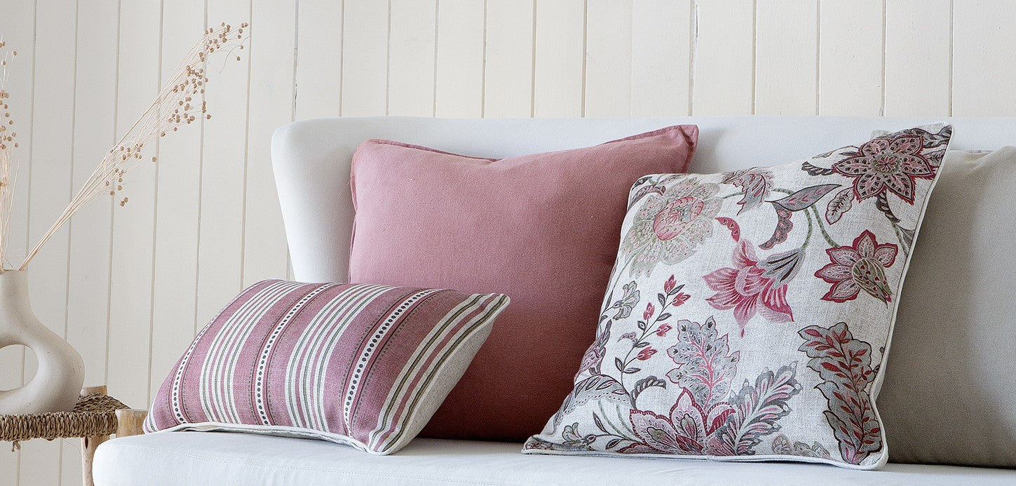 Decorative pillows on a sofa against a wooden panel wall, linen floral 