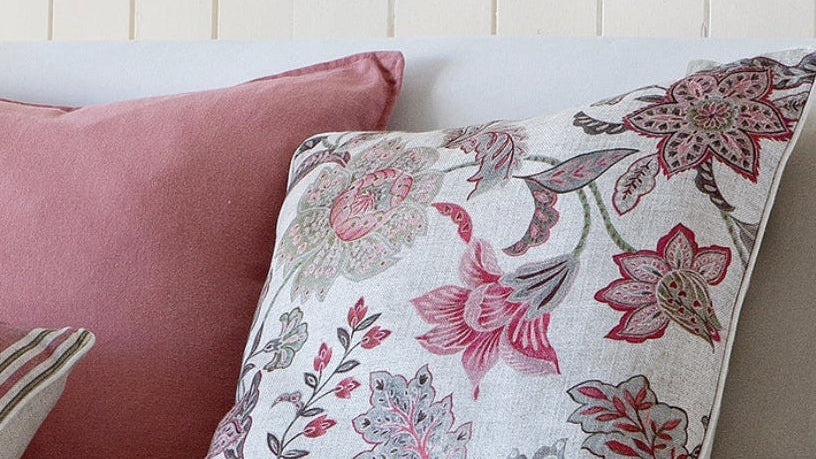 White sofa with patterned cushions in a room with wooden flooring and a light-colored wall.