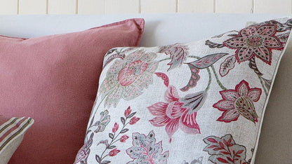 White sofa with patterned cushions in a room with wooden flooring and a light-colored wall.