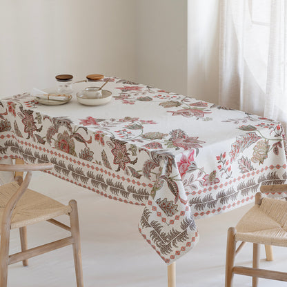 Tablecloth with floral and leaf pattern on a table with chairs in a bright room.