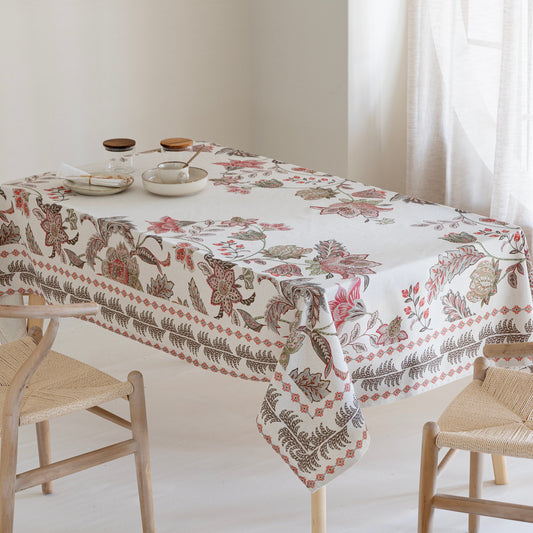 Tablecloth with floral and leaf pattern on a table with chairs in a bright room.