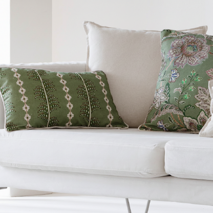 Green patterned pillows on a white sofa against a white wall