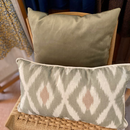 Two decorative pillows on a wicker chair with a patterned background