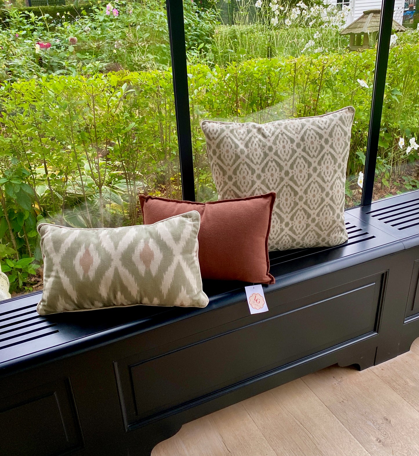 Decorative pillows on a black bench with a garden view
