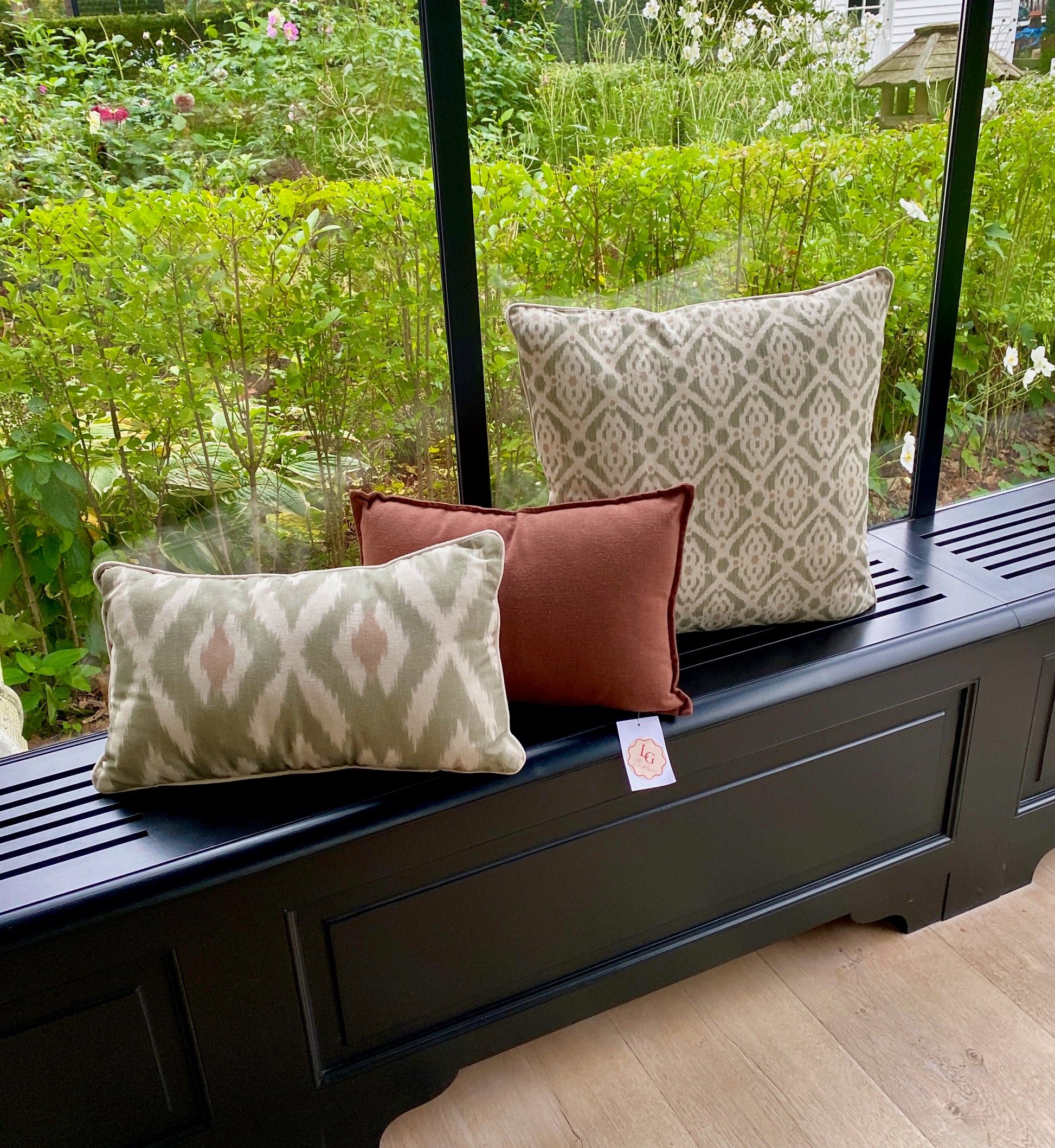 Decorative pillows on a black bench with a garden view