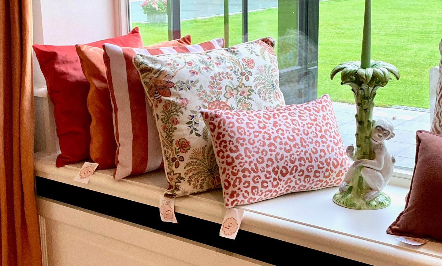 Decorative pillows on a windowsill with a view of greenery outside.