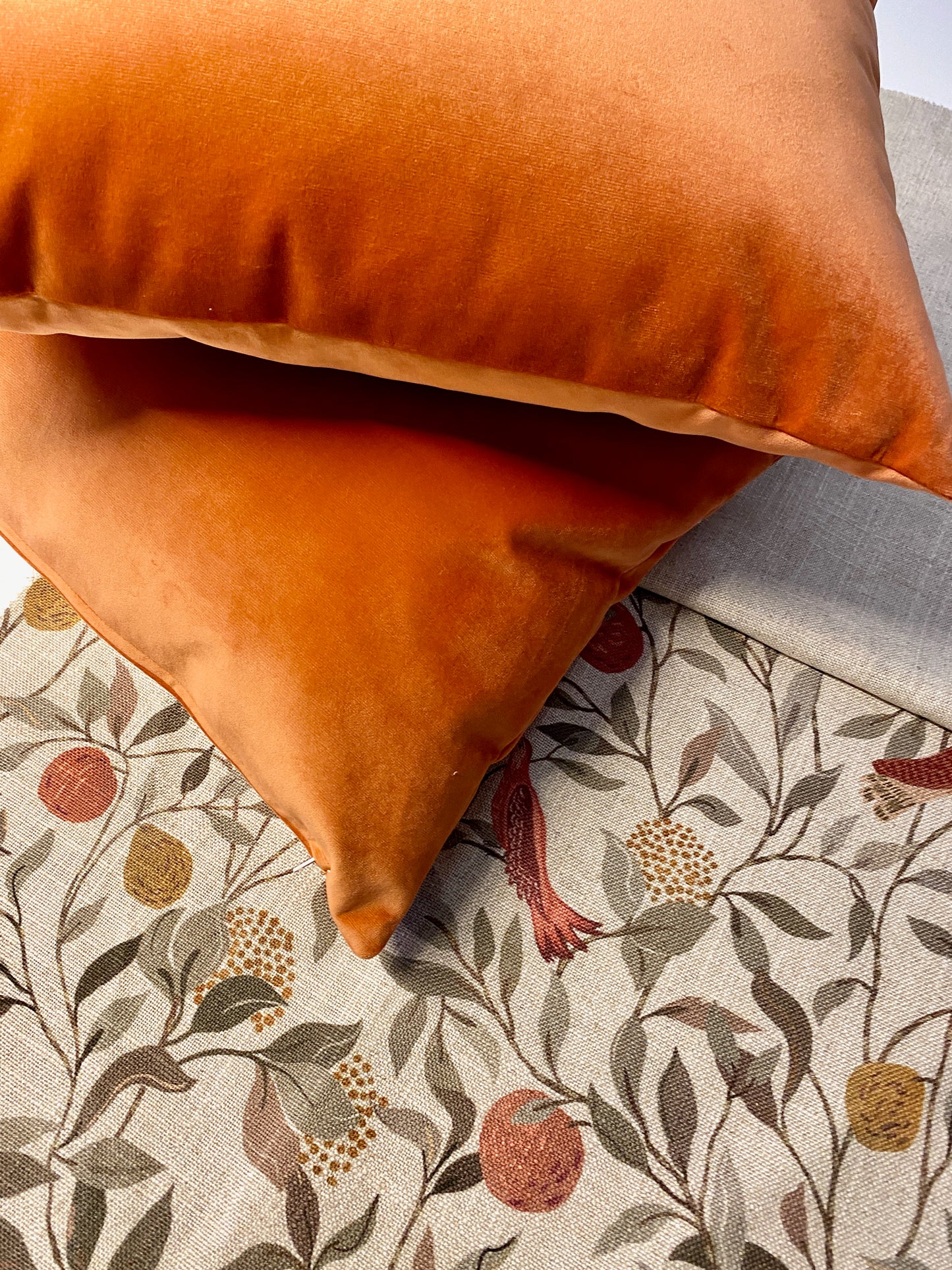 Orange pillow on a floral-patterned fabric surface