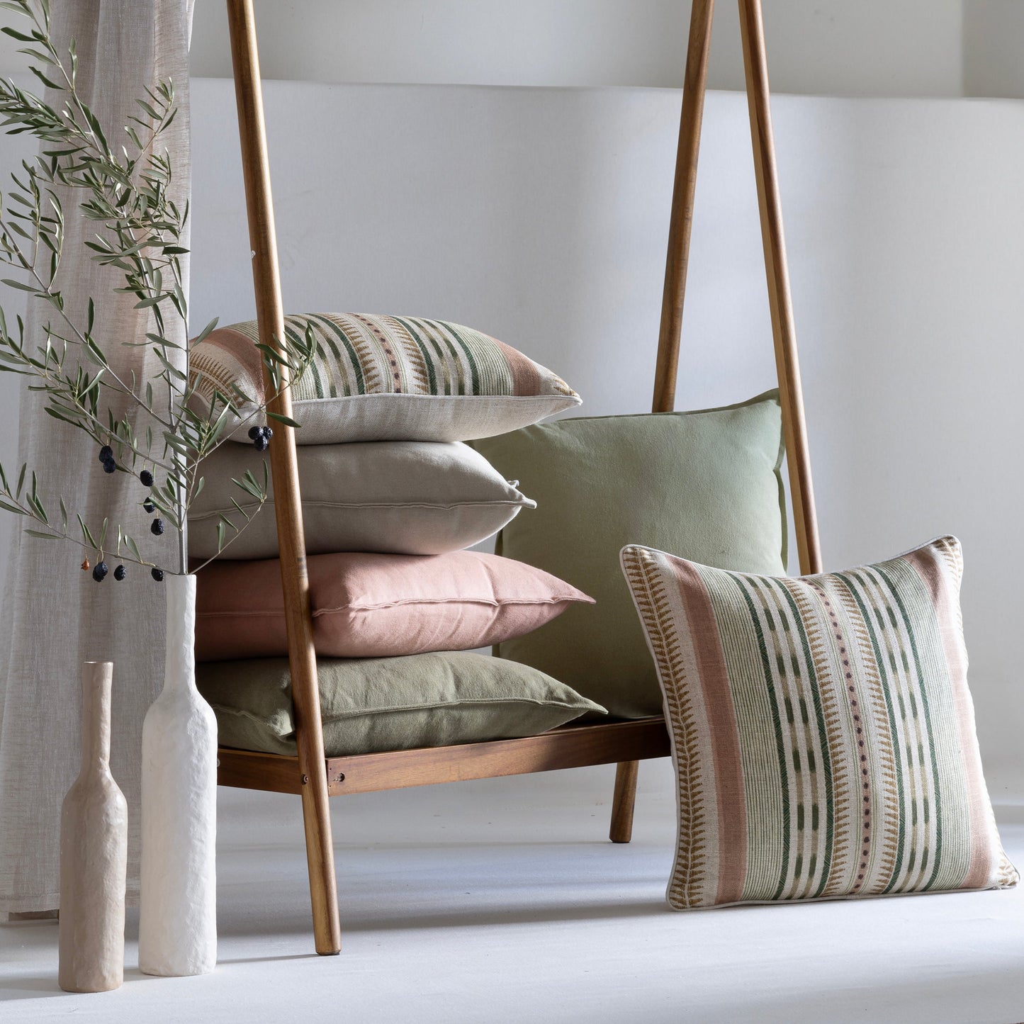 Decorative cushions striped and plain in mix sico linen on a wooden ladder against a white wall