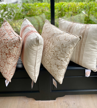 Four patterned pillows William Morris  prints on a black surface with a blurred green outdoor background