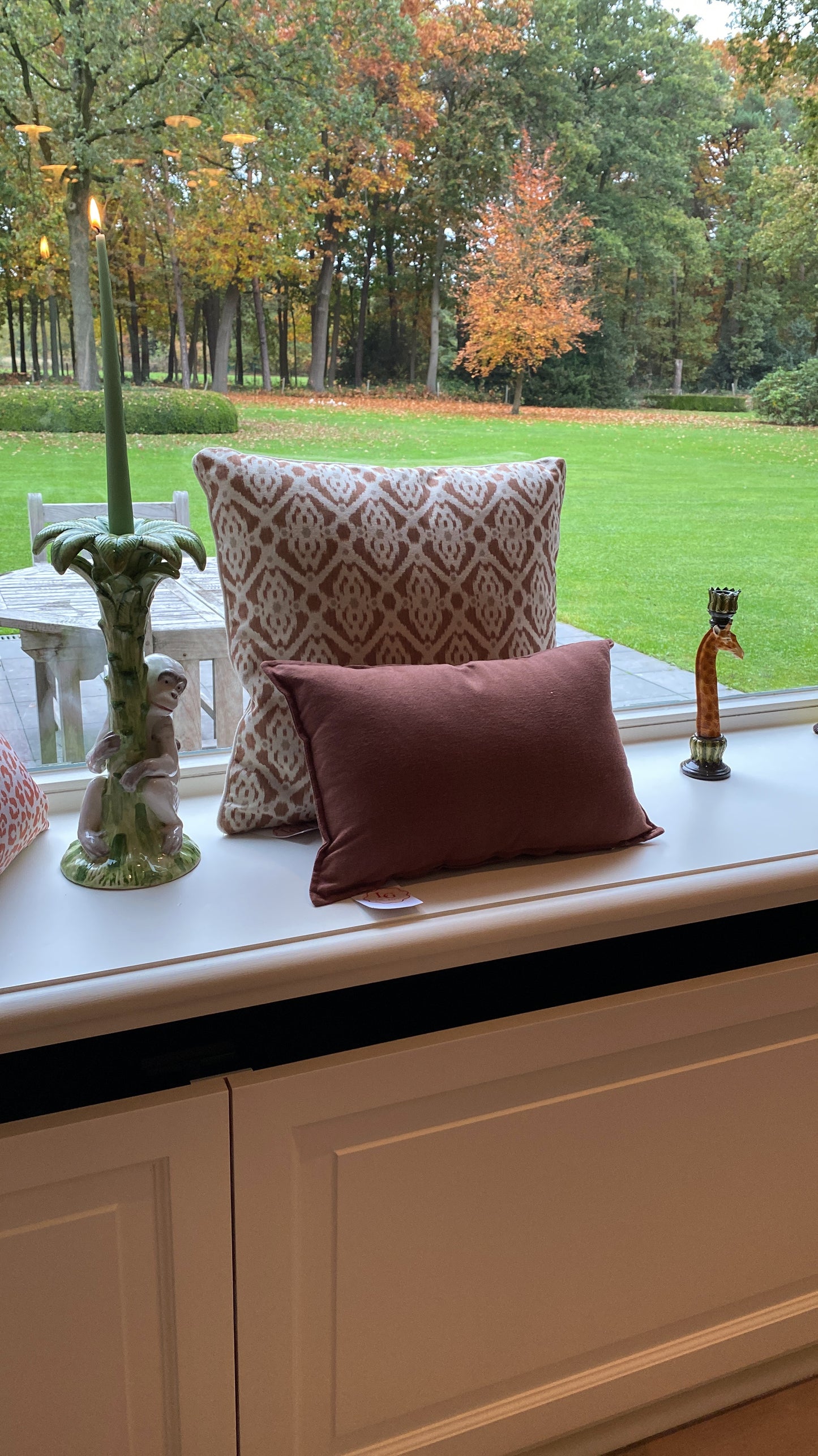 Decorative pillows on a window sill with a garden view