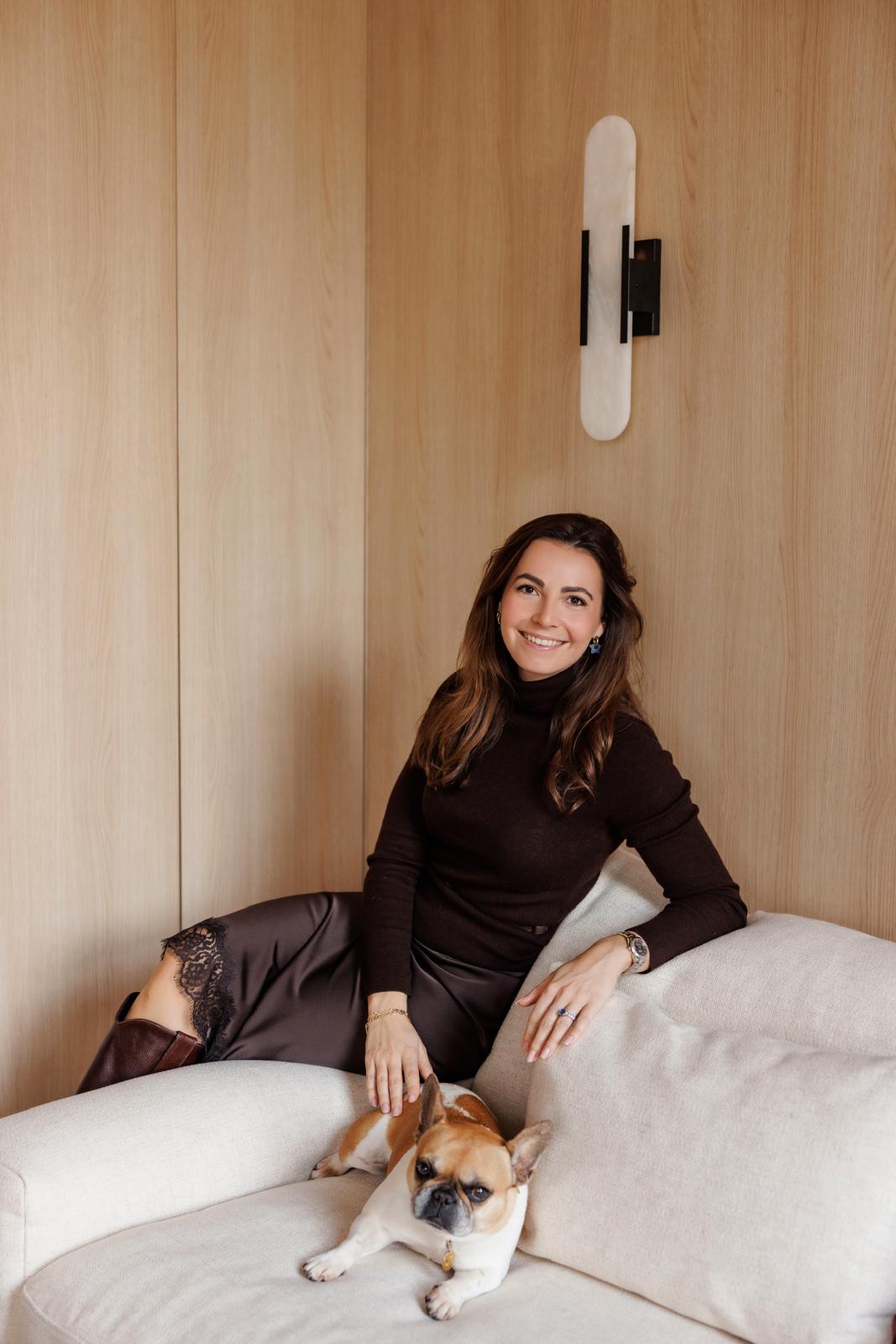 Woman sitting on a couch with a dog in a room with wooden walls. interior decoration